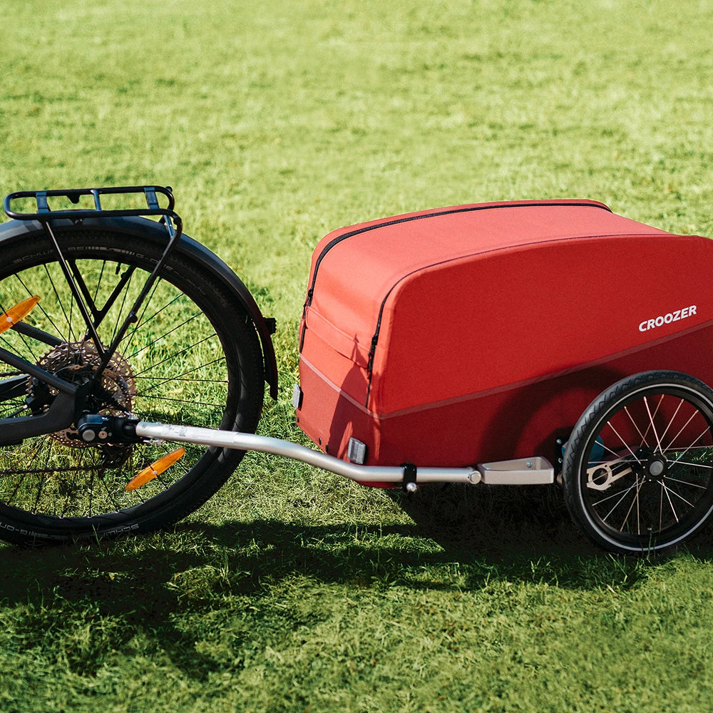 Croozer Cargo Tuure in Lava Red outdoors on grass and attached to bike